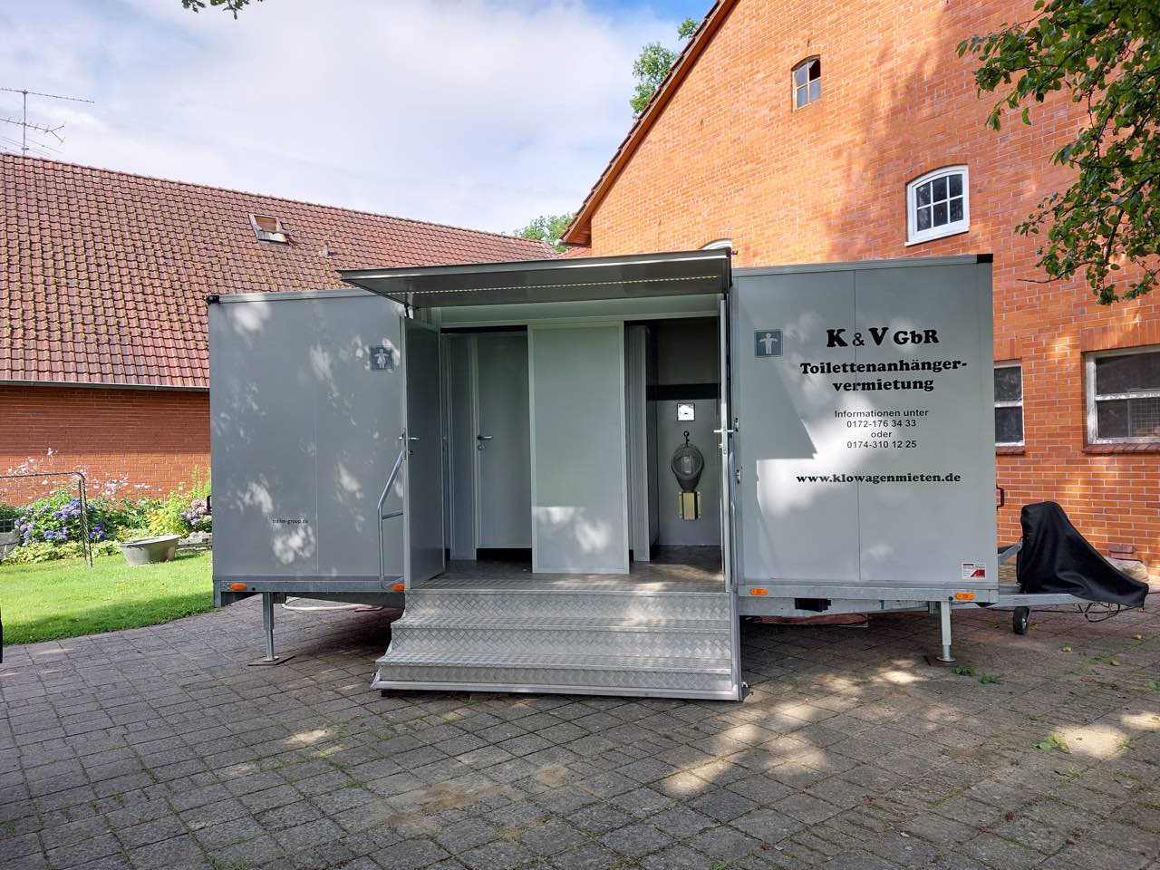 Toilettenanhänger vor einem Fachwerkhaus in einem niedersächsischen Dorf