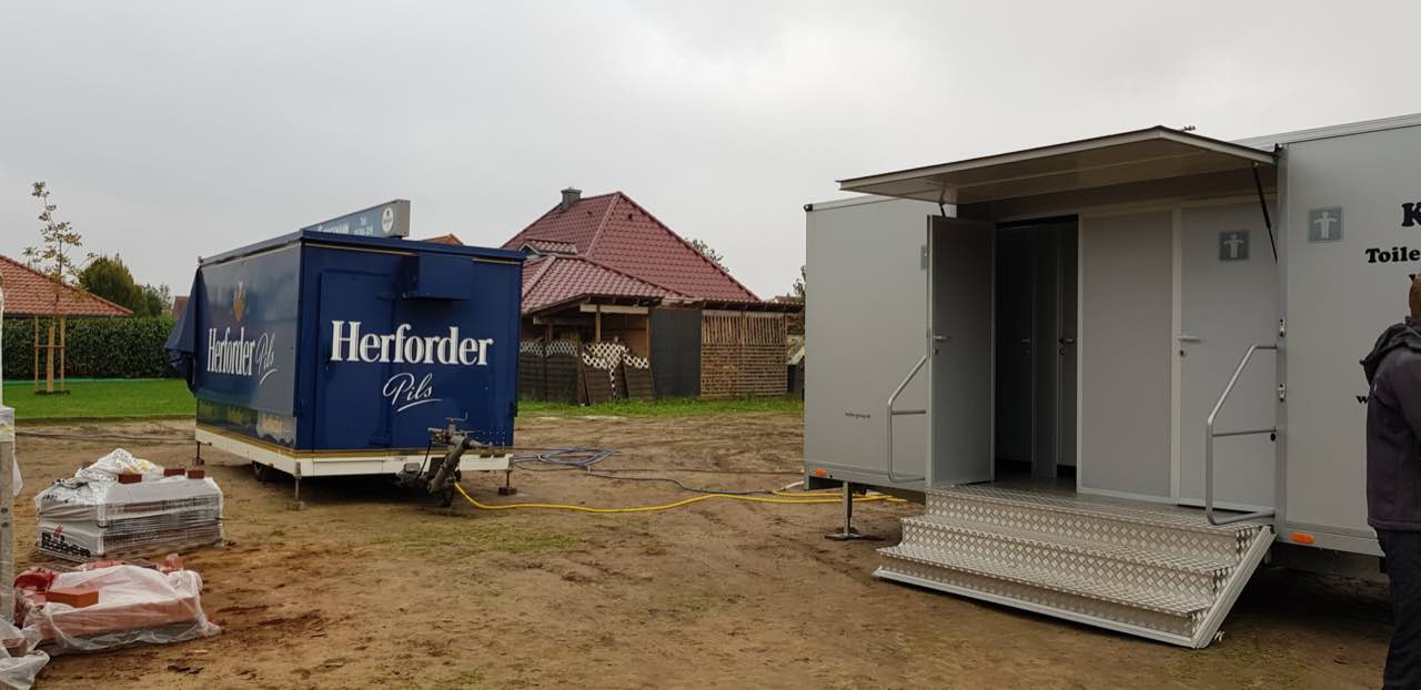 Toilettenanhänger neben einem Bierwagen auf einem Festplatz