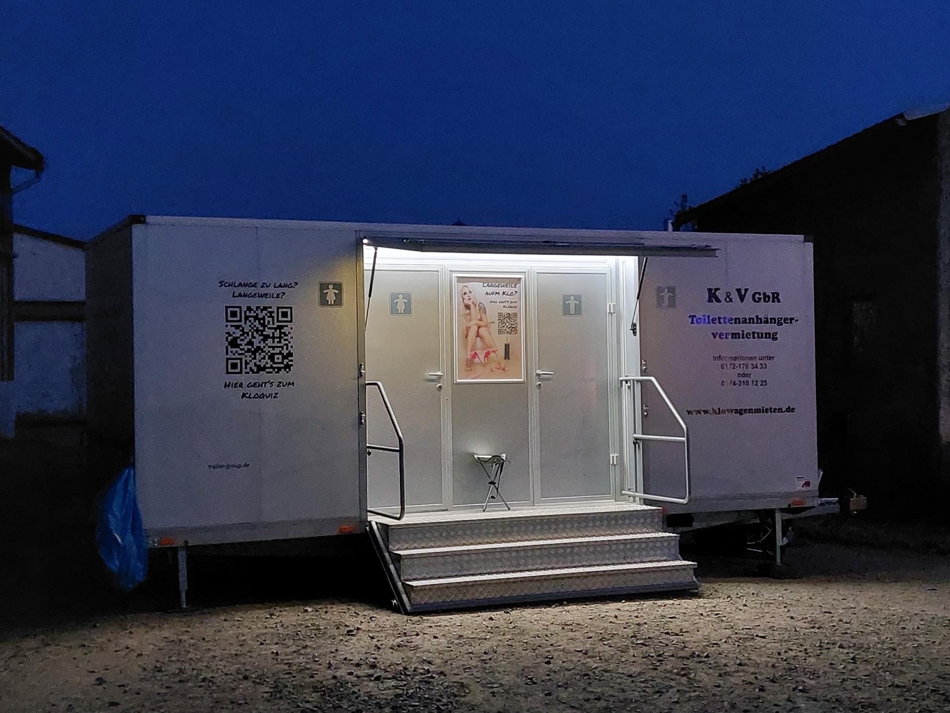 Premium-Toilettenanhänger von K&amp;V in der Abenddämmerung mit warm beleuchtetem Innenraum
