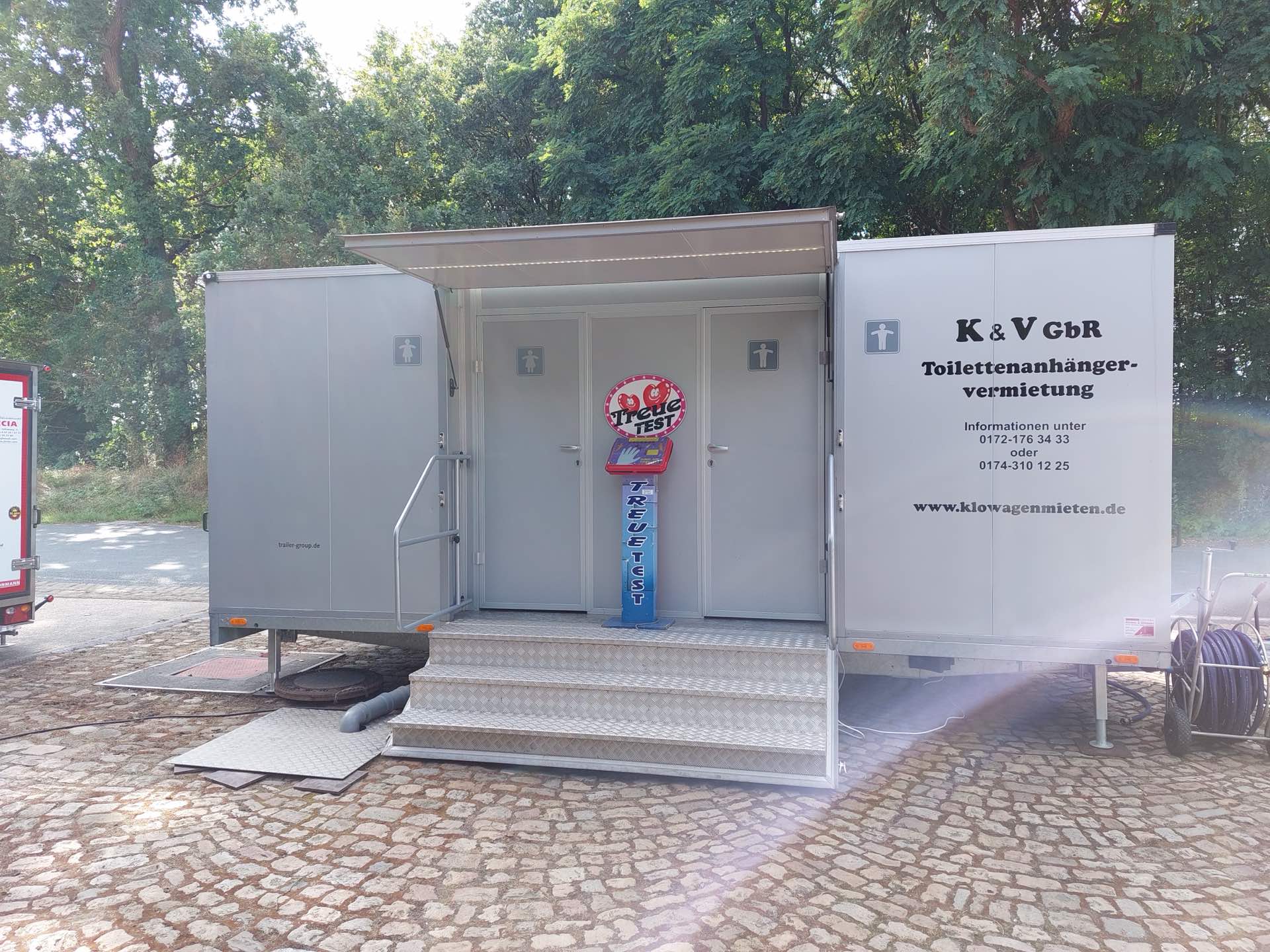 Aufgebauter Premium-Toilettenanhänger mit geöffnetem Vordach