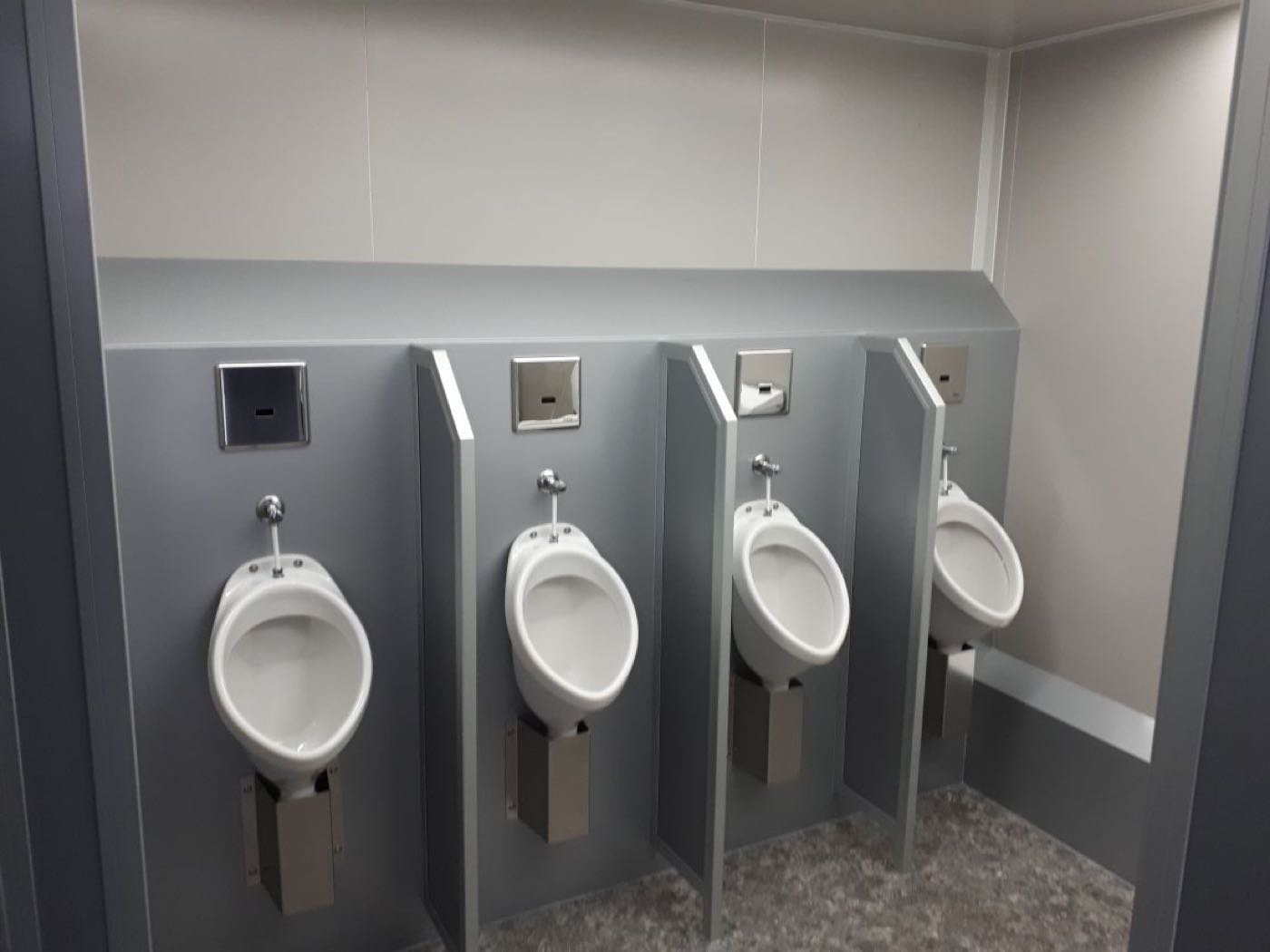 Vier berührungslose Pissoirs im Herrenbereich des Premium-Toilettenanhängers