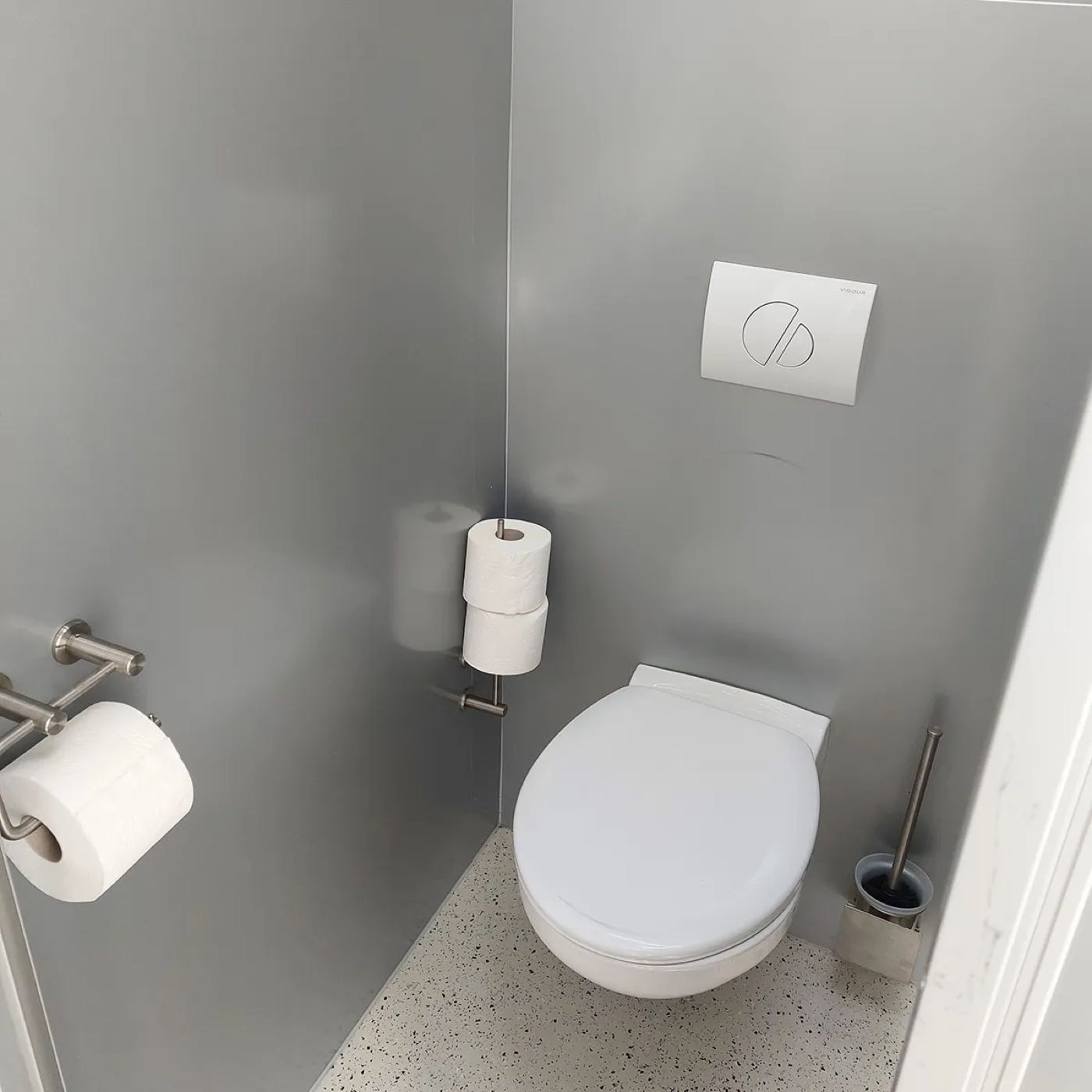 Helle WC-Kabine mit Wand-WC, Reserverolle und Bürste