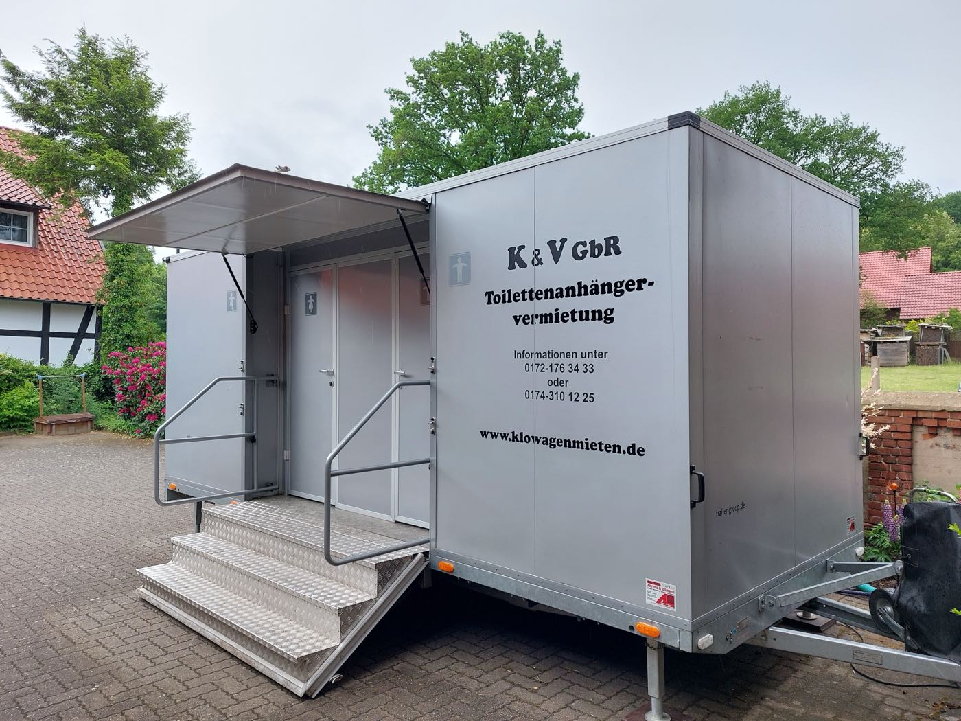 Premium-Toilettenanhänger in einer Hofeinfahrt vor einem Fachwerkhaus